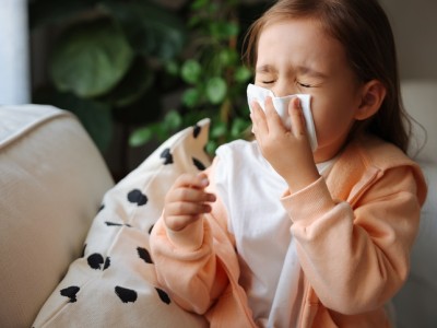 Toddler sneezing into tissue